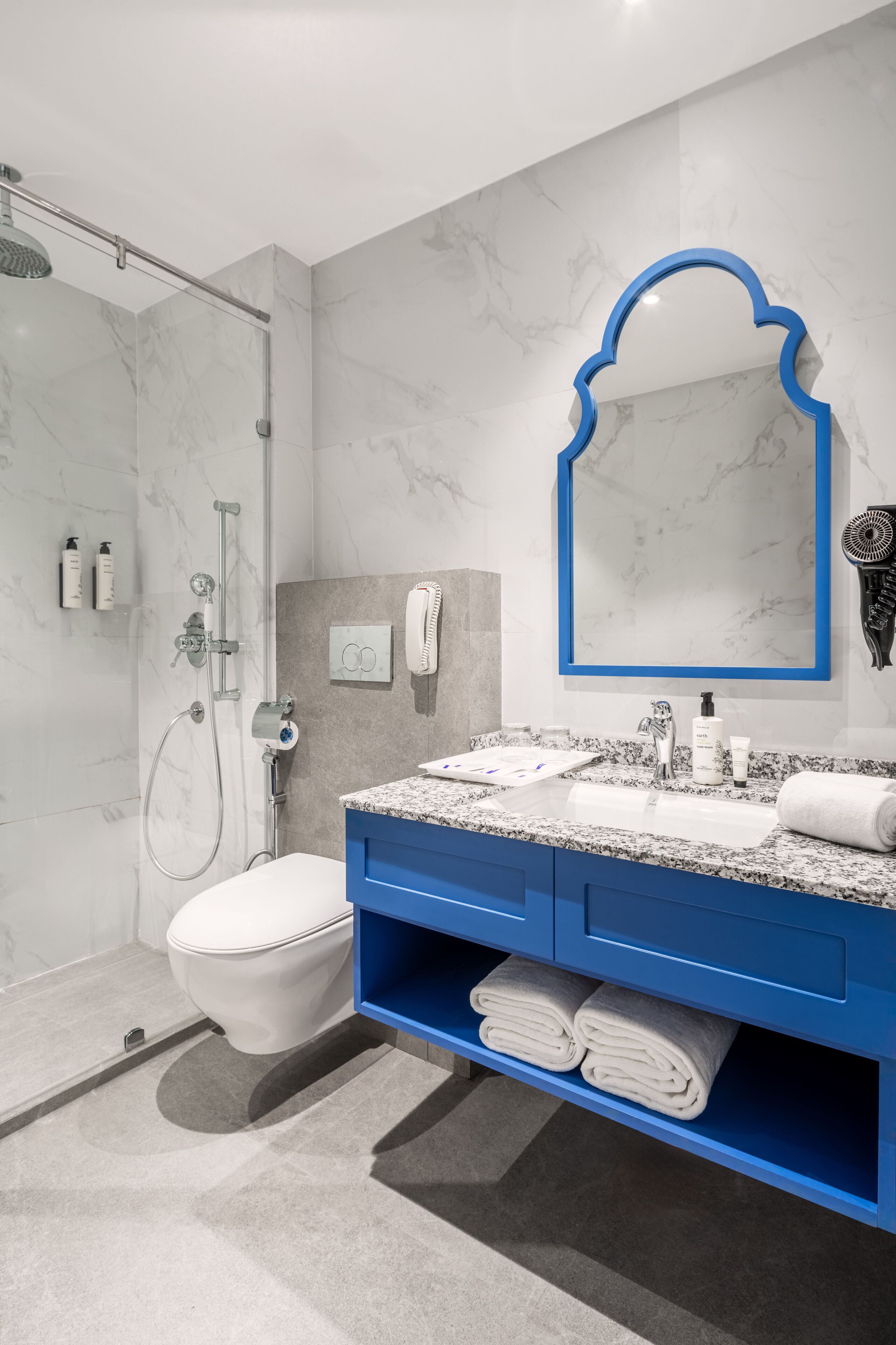 Une salle de bain moderne équipée d’une douche, de toilettes et d’un meuble-lavabo avec un meuble bleu.
