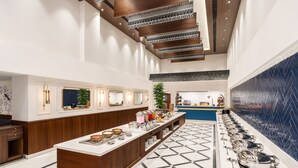 A modern hotel lobby with a long buffet counter, a reception desk, and a patterned floor. - MJ Sarovar Portico Haridwar (Haridwar)