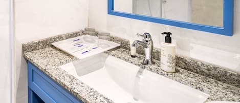 A modern bathroom with a white sink, blue vanity, and a large mirror with a blue frame.