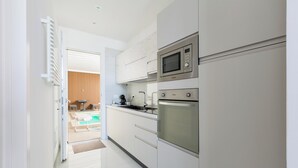 A modern kitchen with stainless steel appliances, white cabinetry, and a view into a dining area with a table and chairs. - 4153 Pasitea Luxury Suite by Barbarhouse (Squinzano)