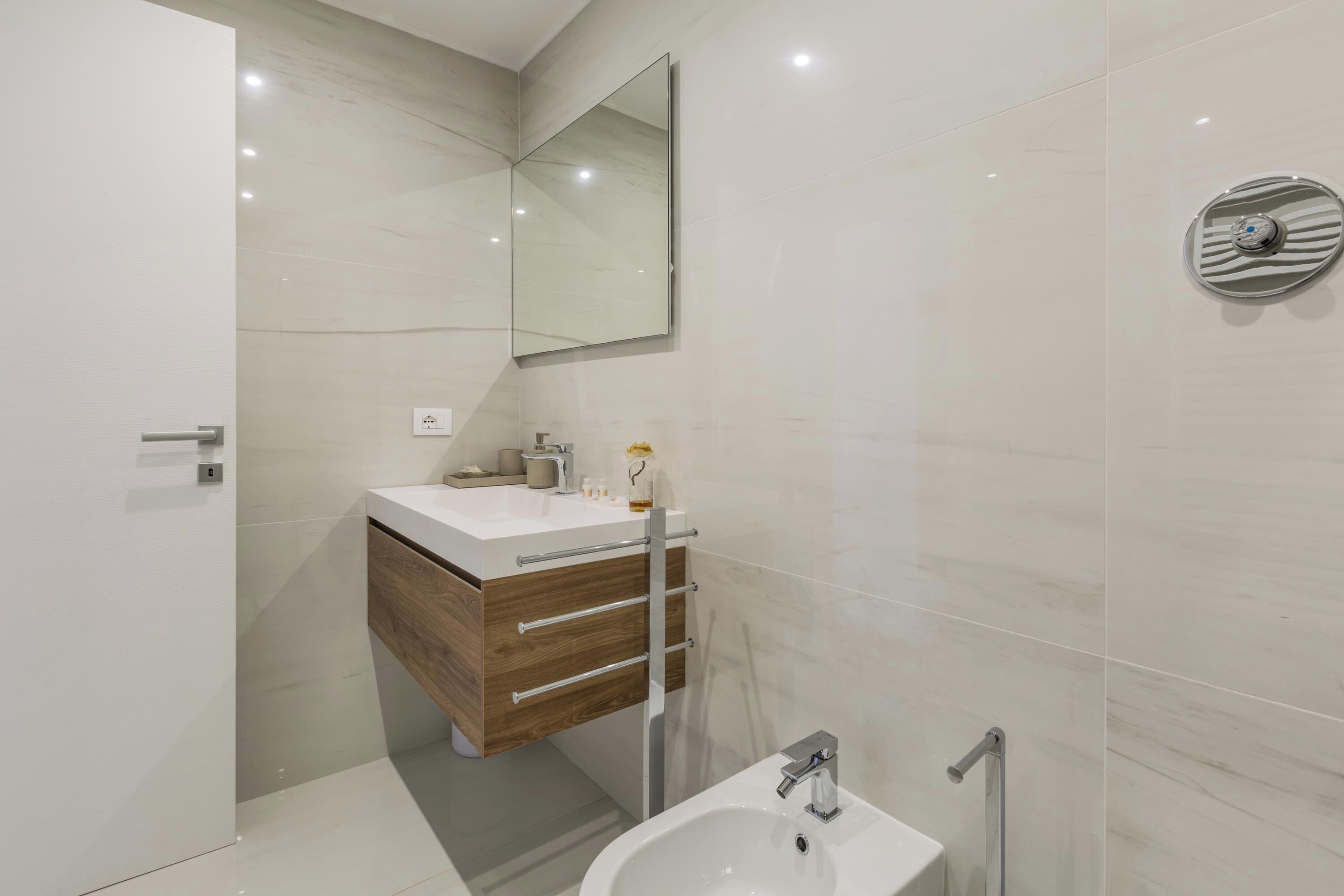 A modern bathroom with a white vanity, a large mirror, and a shower area.