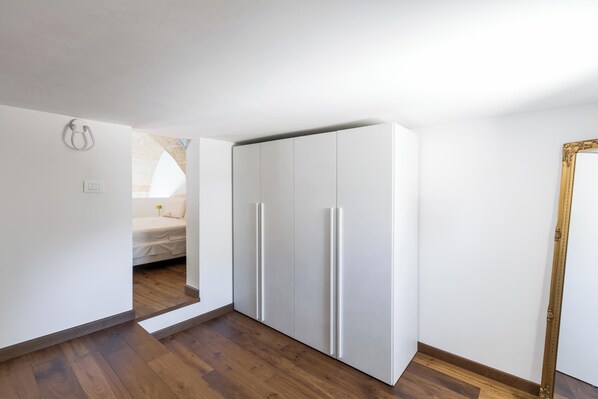 A bedroom with a bed, a wardrobe, and a mirror.