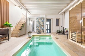 A swimming pool with a wooden deck, a staircase, and a view of the interior.