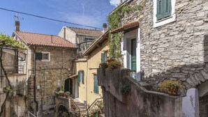 Eine enge Gasse mit Steinhäusern, einer kleinen Treppe und Kübelpflanzen.