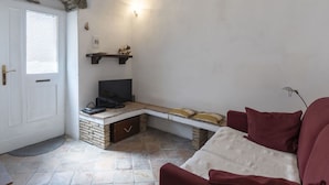 Ein gemütliches Wohnzimmer mit Kamin aus Stein, einem Fernseher und einer bequemen Sitzecke.