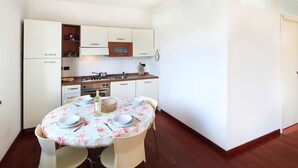 A compact kitchen with white cabinets, a wooden countertop, and a dining table set for four. - Cosy apartment for 4 people with A/C, WIFI, TV and terrace (Pietrasanta)
