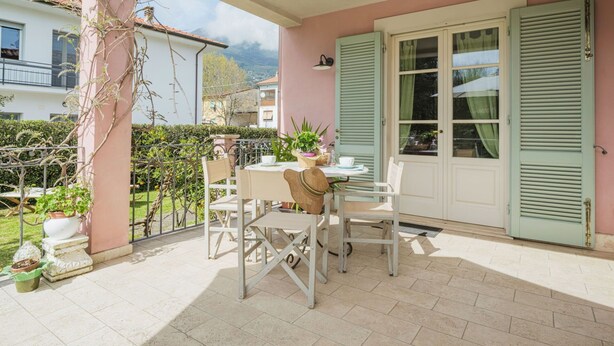 A covered patio with a table and chairs, a door with shutters, and potted plants. - Nice apartment for 3 guests with WIFI, TV and terrace (Camaiore)