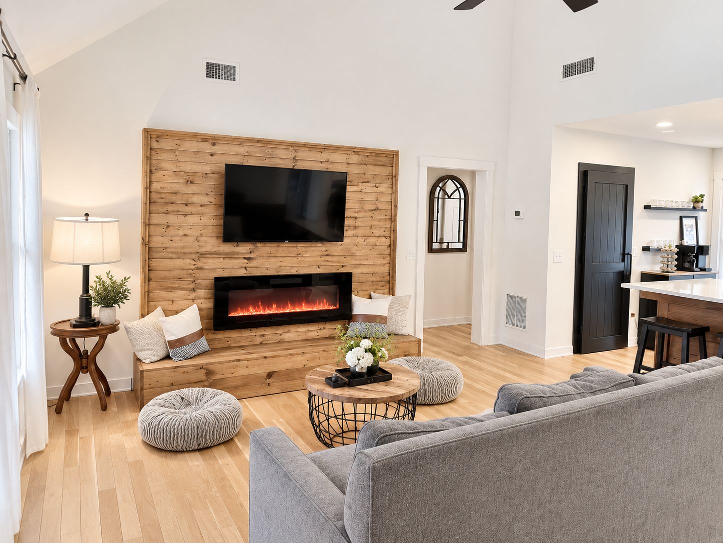 A modern living room with a fireplace, a flat-screen TV, and a dining area.