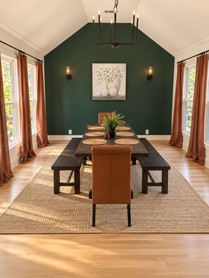A dining room with a high ceiling, a dark green wall, a chandelier, a framed artwork, and a table set for four. - Milton/Alpharetta 5BR Home 5-bds/up to 12 guests - House & Event Venue (Alpharetta)