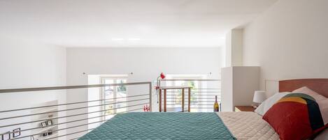 A bedroom with a green quilted bedspread, a wooden headboard, and a bedside table with a lamp.