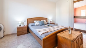 Une chambre à coucher avec un lit en bois, des tables de chevet, une commode, un petit meuble en bois et une fenêtre avec des rideaux.