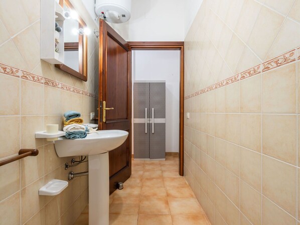 Une petite salle de bain avec un lavabo, un miroir et un porte-serviettes.