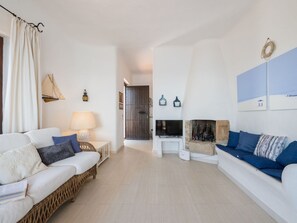 A living room with a sofa, a TV, a fireplace, and a wall with artwork. - Nice apartment in villa for 8 guests with A/C, WIFI, TV and patio (Pula)