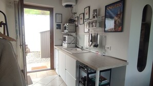 Een keuken met betegelde vloer, witte kasten, een aanrecht en een plafondventilator.