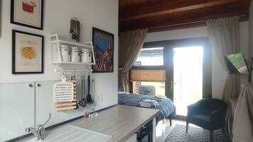 A kitchen with a sink, cabinets, and a ceiling fan. There are framed pictures on the wall and a window with curtains.