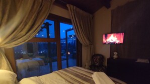 Een hotelkamer met een bed, een aan de muur bevestigde televisie en uitzicht op het exterieur.