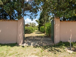 A pathway leading through a gate into a landscaped area with trees and shrubs.