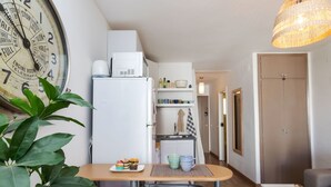 Una cocina compacta con refrigerador, microondas y un pequeño comedor con mesa y sillas.