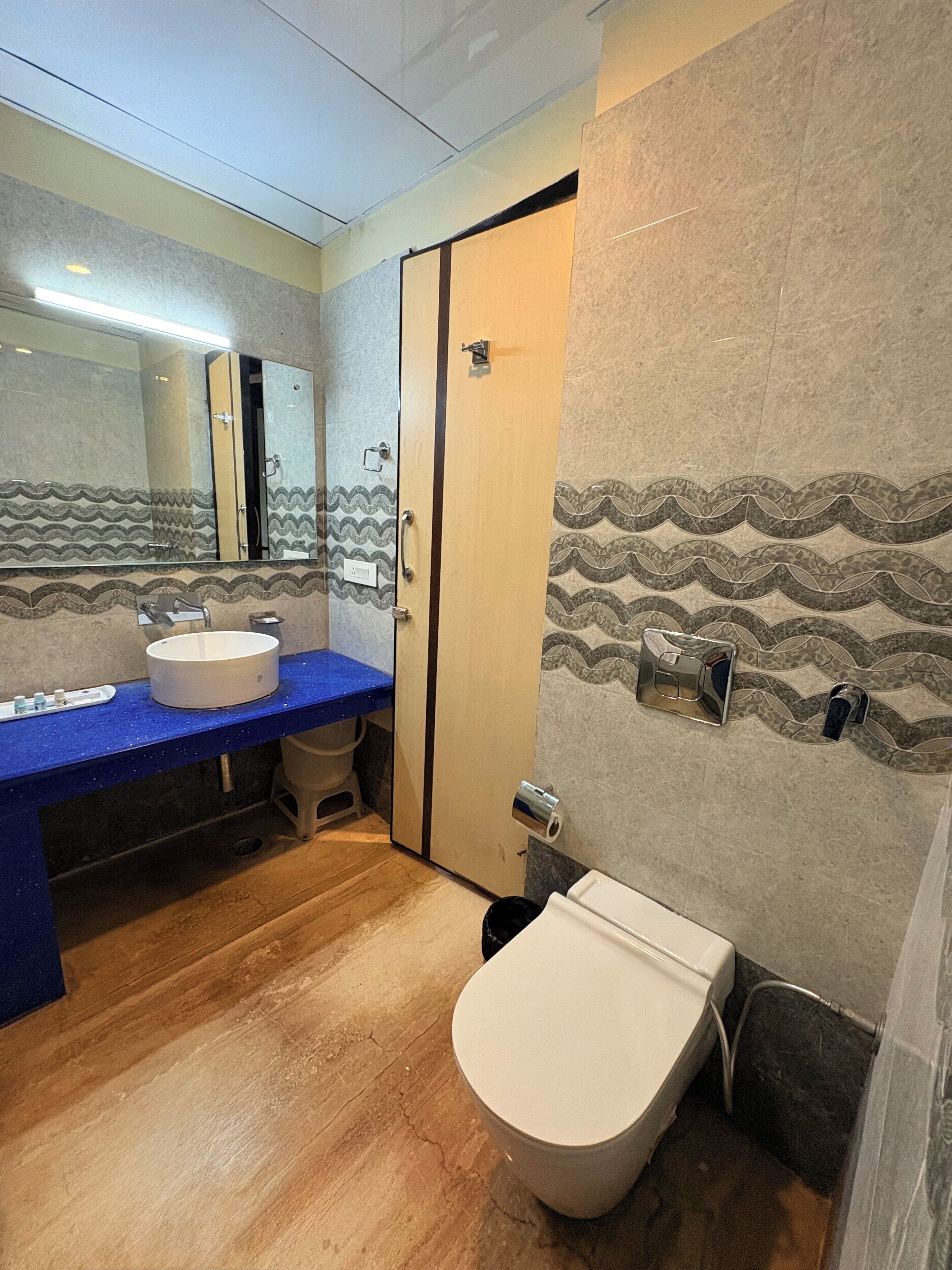 Ein Badezimmer mit blauer Ablage, einem weißen Waschbecken, einer Toilette und einem Spiegel.