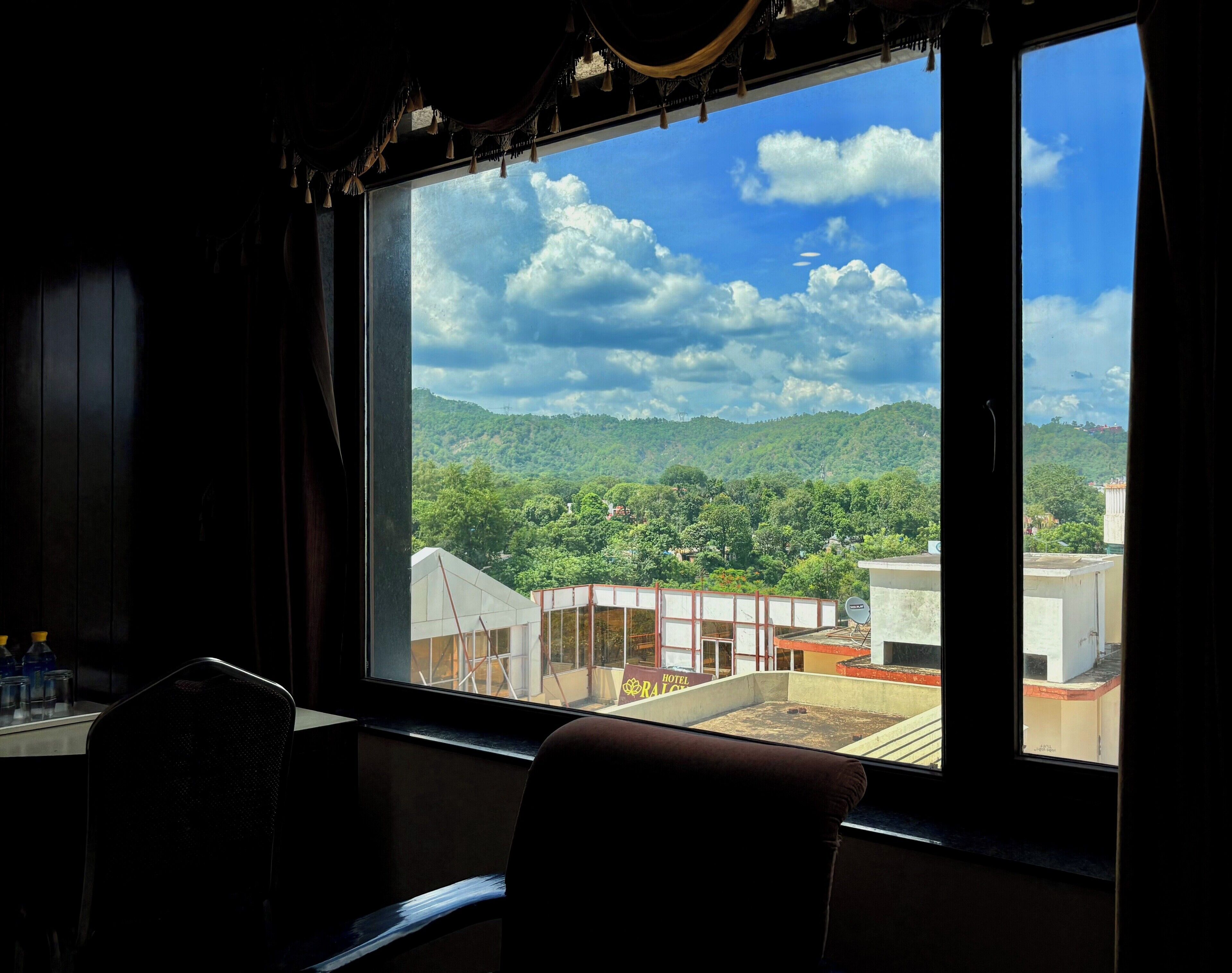 Una habitación con un ventanal amplio que ofrece vistas a un paisaje montañoso y el letrero de un hotel.