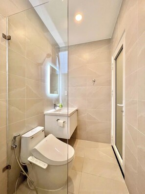 Un baño moderno con inodoro, lavamanos y cabina de ducha de vidrio.