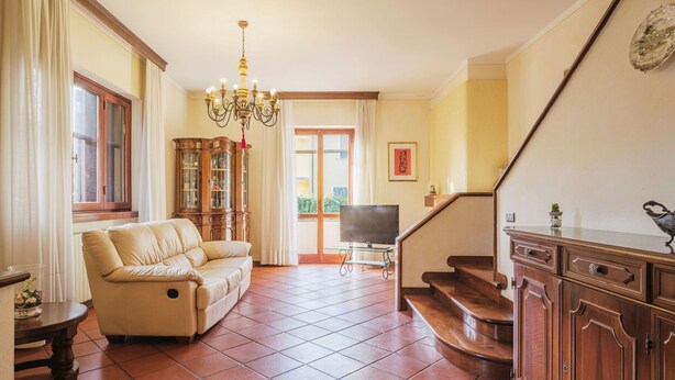 A living room with a sofa, a television, a wooden cabinet, and a staircase.