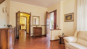 A spacious living room with a sofa, a wooden cabinet, and a tiled floor.
