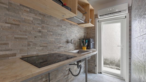 A modern kitchen with a stone backsplash, a built-in stove, and a window overlooking a garden. - 4145 Giusy House by Barbarhouse (Lecce)