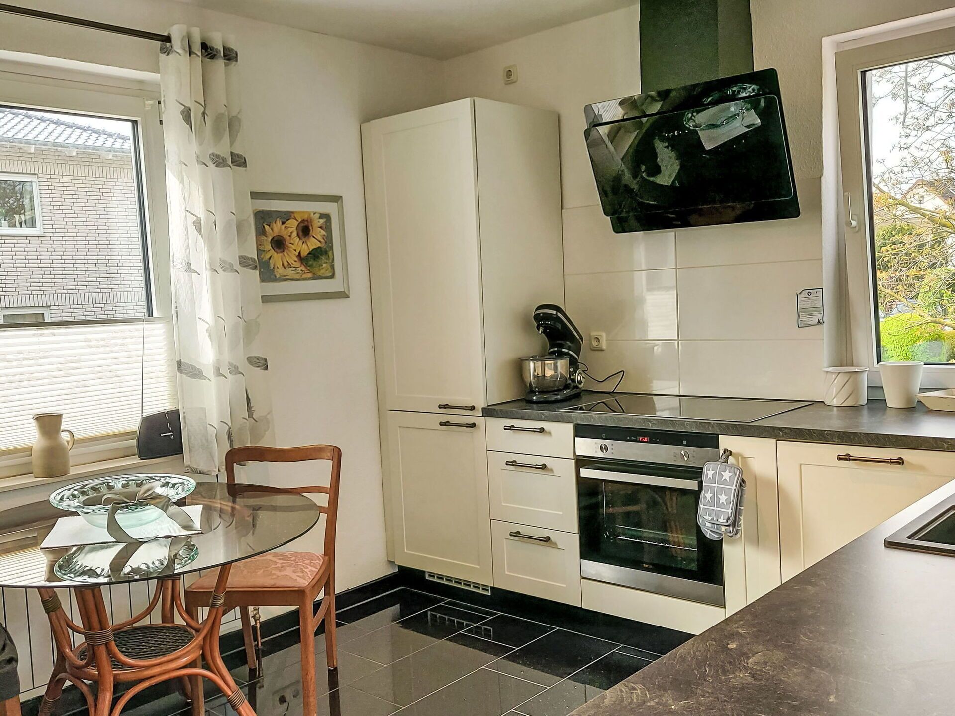 A kitchen with a dining table, chairs, a coffee maker, and a TV mounted above the counter.