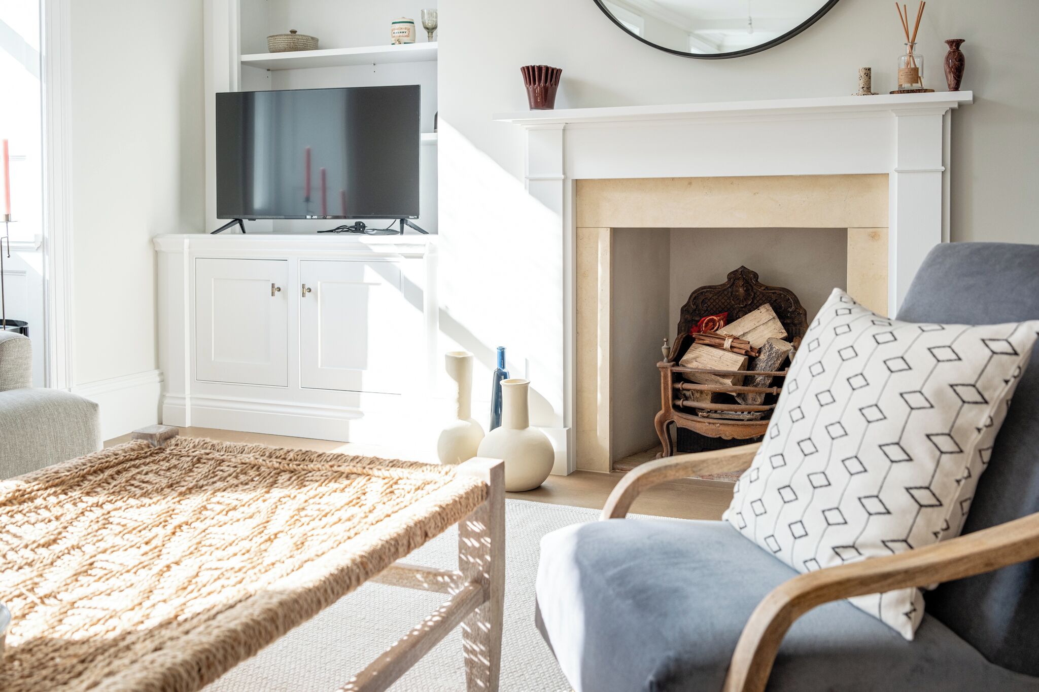 A living room with a television, white cabinets, a fireplace, and a blue armchair.