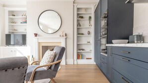 Una cocina moderna con armarios azul oscuro, una chimenea blanca y un espejo redondo en la pared.