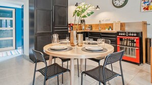 A modern kitchen with dark cabinets, a round dining table, and black chairs. - Wonderful  villa for 5 people with WIFI and pets allowed (La Richardais)