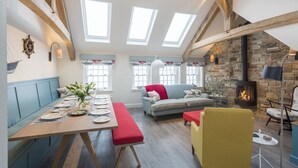Un loft spacieux avec de hauts plafonds, des fenêtres de toit, une cheminée en pierre et un coin salon confortable.