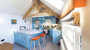 Una cucina con mobili blu, un'isola in marmo e sgabelli di legno.