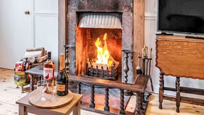 Una habitación acogedora con chimenea, televisión y una mesa con vasos y una botella.