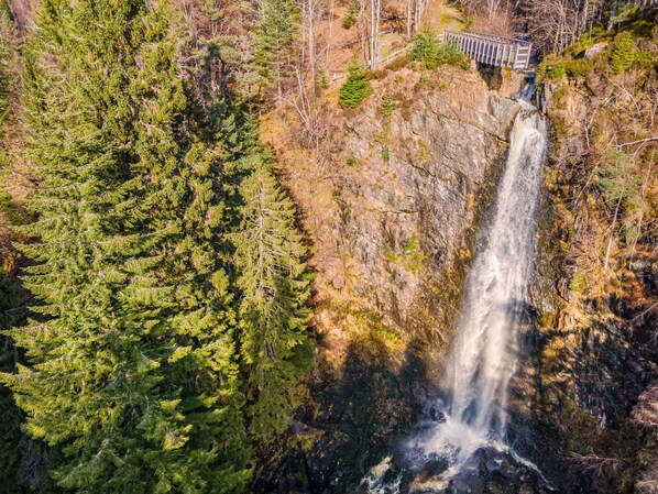 A waterfall with a wooden bridge and dense forest.