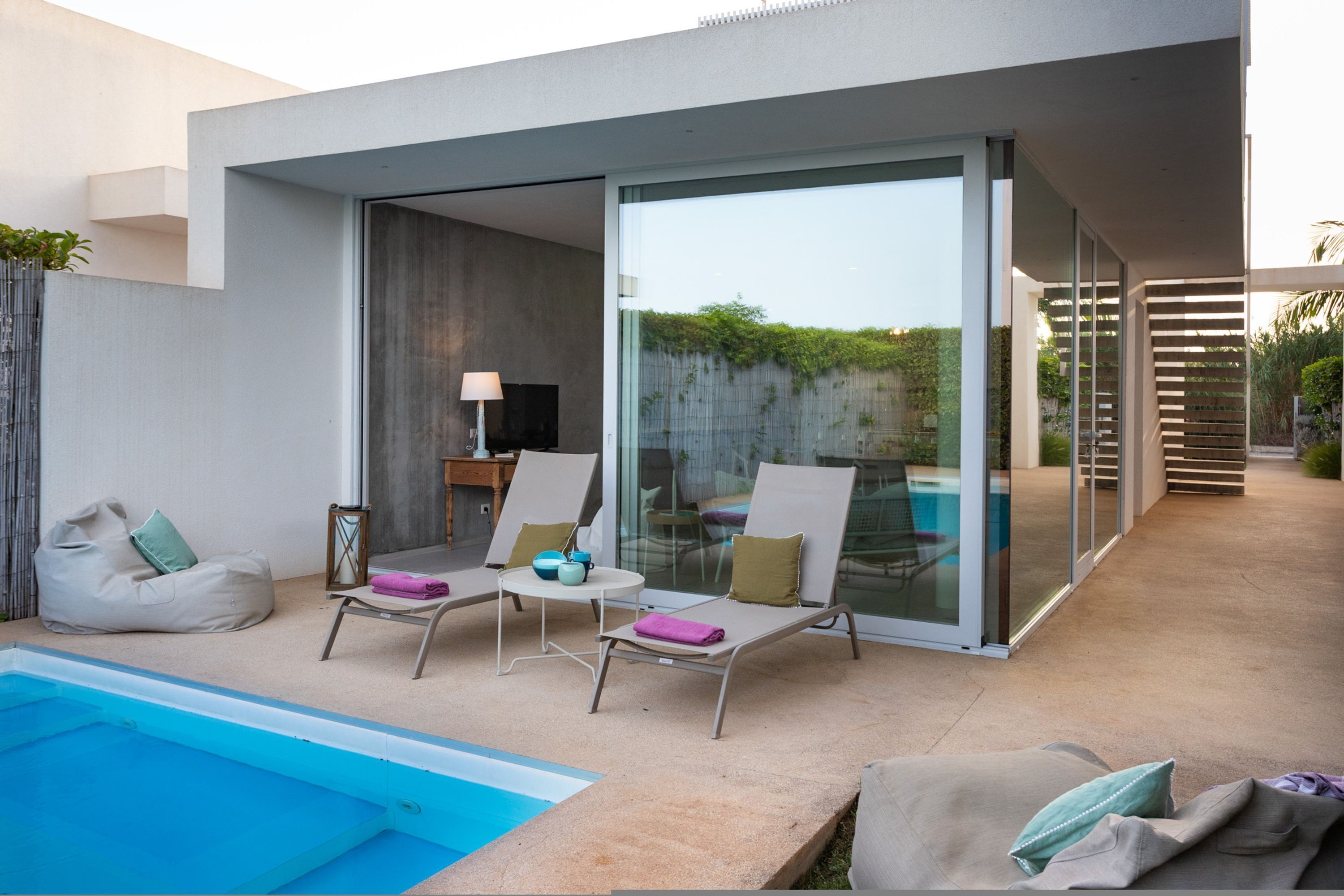 A modern outdoor pool area with lounge chairs and a glass-enclosed patio.