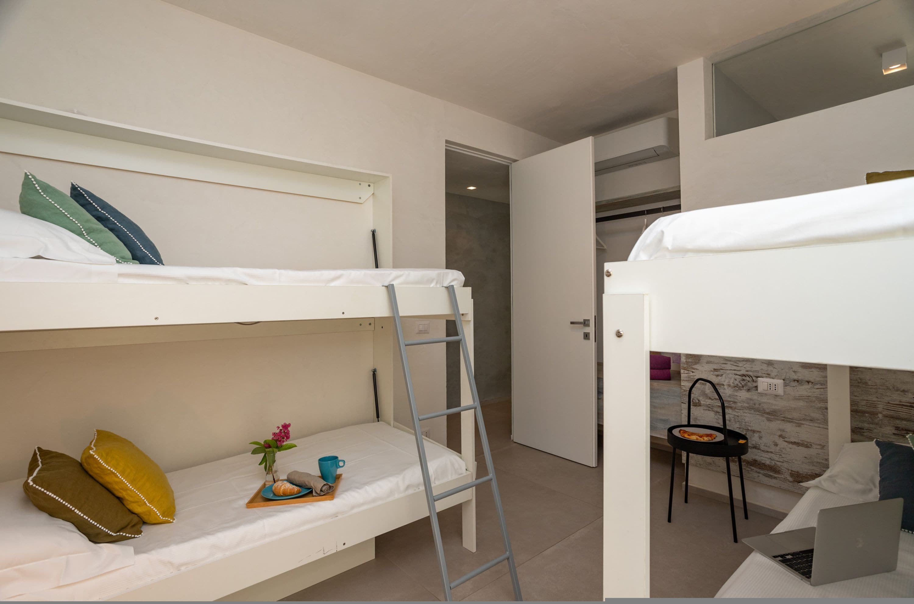 A bunk bed room with a ladder, a desk, and a chair.