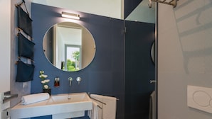 A modern bathroom with a large mirror, a white sink, and a shower area.