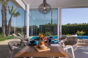 A dining area with a table set for breakfast, overlooking a swimming pool and garden. - Villa Mandorlo 4 Emma Villas (Ragusa)