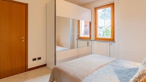 A bedroom with a bed, a wardrobe, a mirror, and a window. - Cosy apartment for 2 people with WIFI, TV and balcony (Colico)