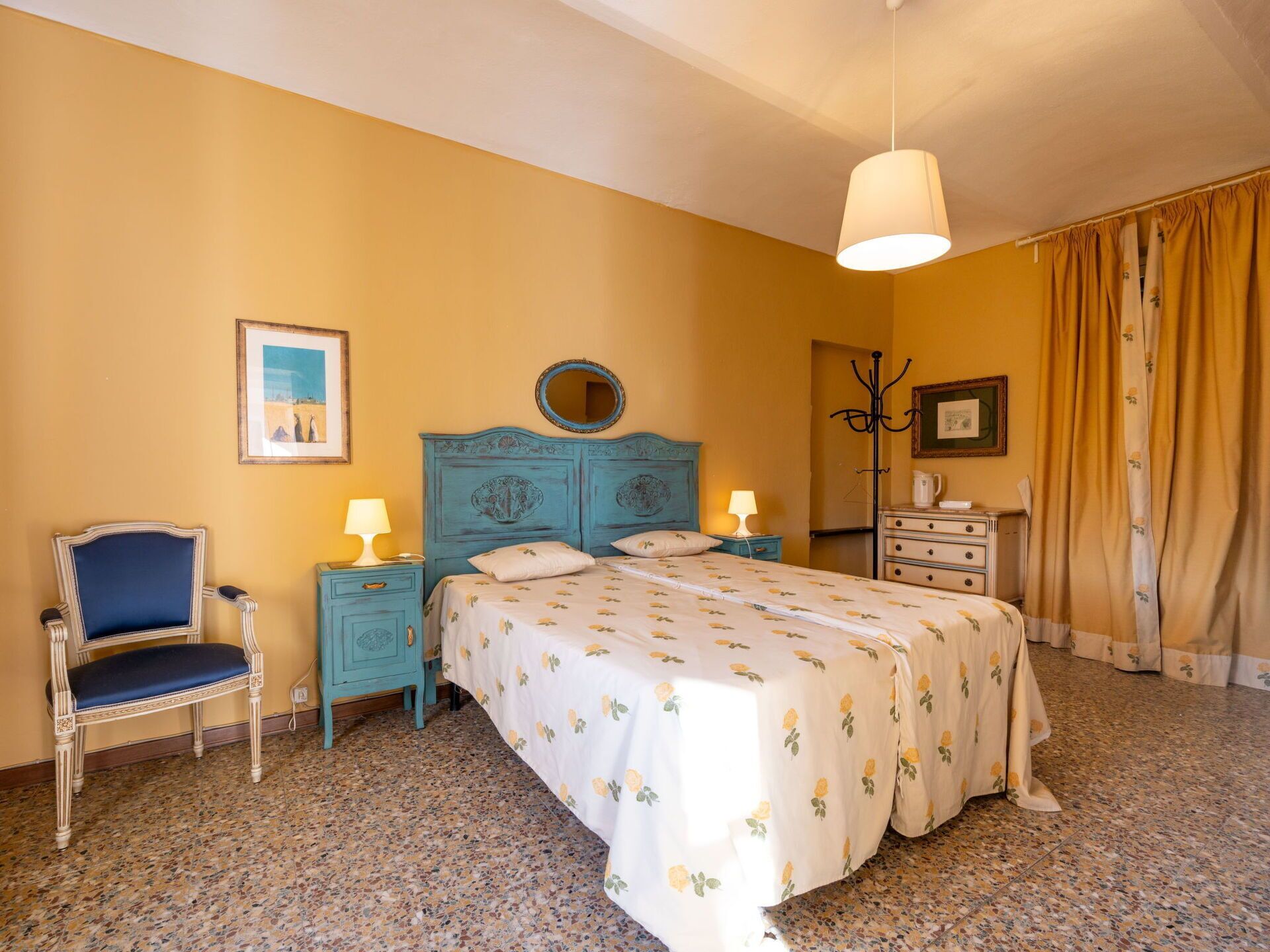 Ein Schlafzimmer mit Bett, Stuhl, Nachttisch, Kommode und Spiegel.