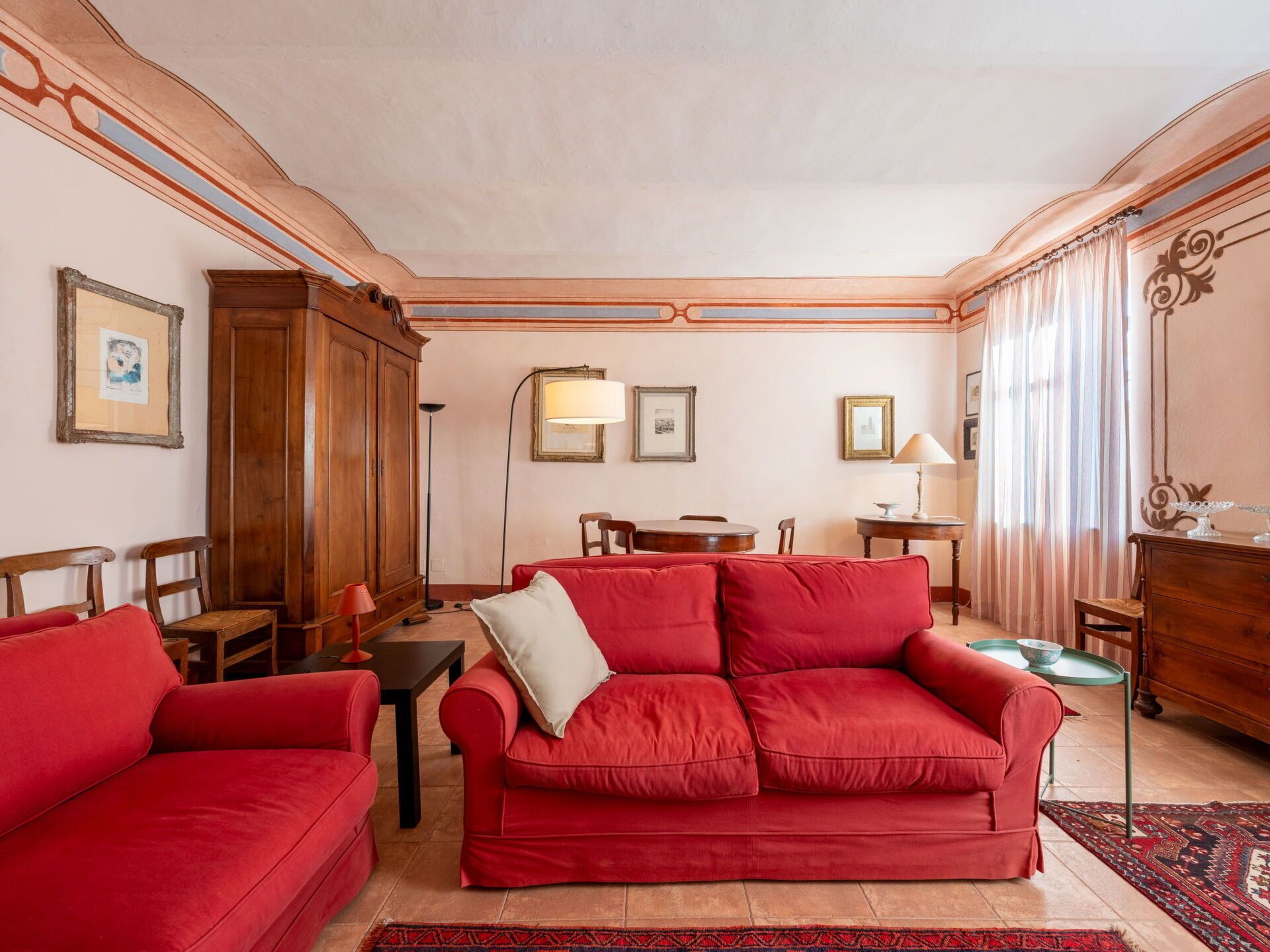 Un salon avec un canapé rouge, des meubles en bois et un tapis à motifs.