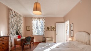 Une chambre à coucher avec un lit, un bureau, une chaise, une commode et une porte.