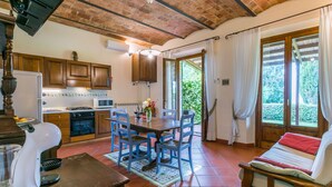 A cozy kitchen with wooden cabinets, a dining table with blue chairs, and a red sofa. - Nice apartment in villa for 4 people with A/C, WIFI, pool, TV and panoramic view (Montaione)