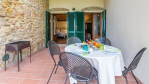 Ein Zimmer mit Stehwänden, einem Bett und einem für das Essen gedeckten Tisch, mit grünen Fensterläden.