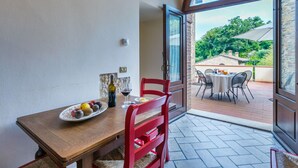 A dining area with a wooden table, red chairs, and a plate of fruit. - Stunning  villa for 16 guests with WIFI, private pool, A/C, TV and panoramic view (Montaione)