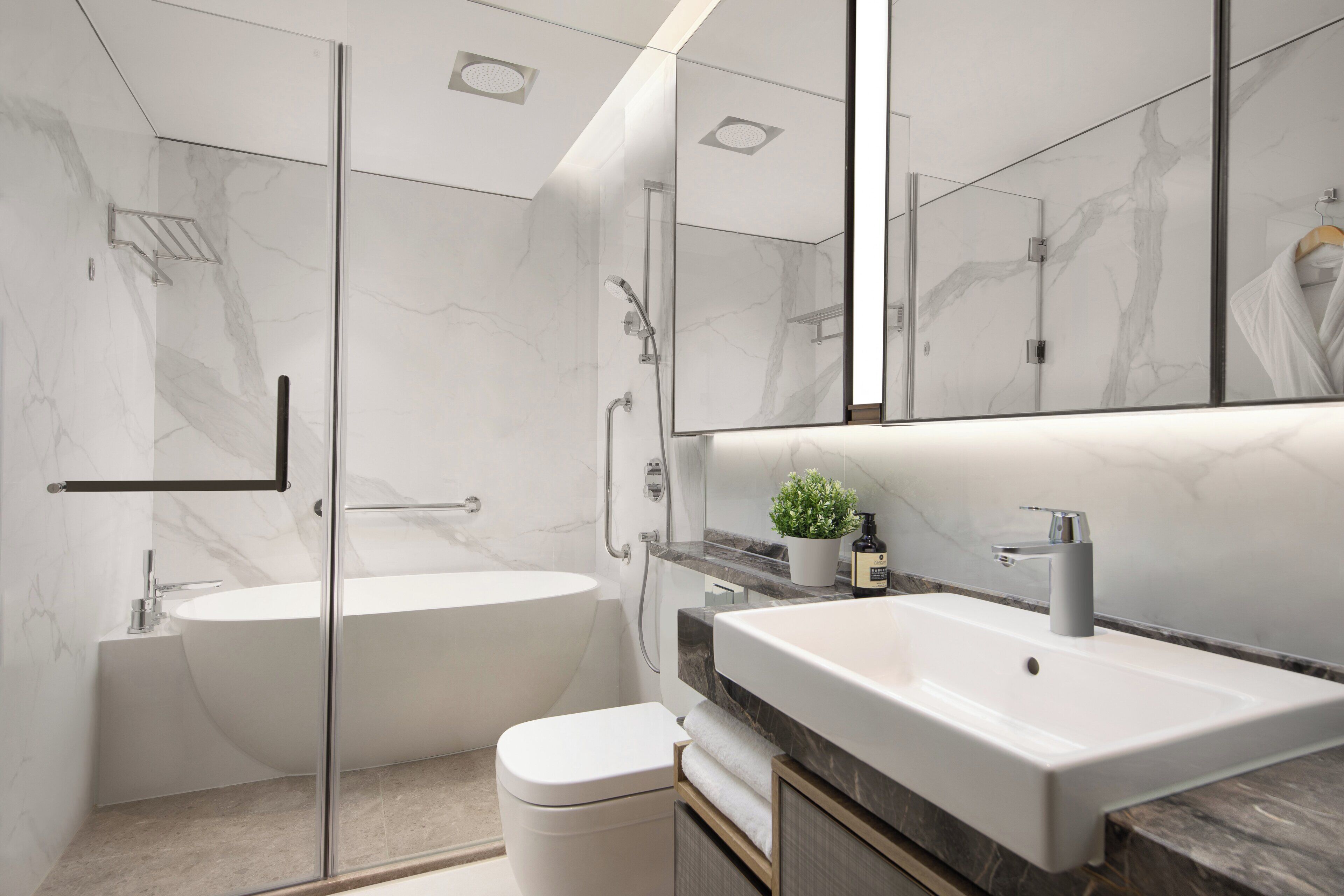 A modern bathroom with a glass-enclosed shower, a freestanding bathtub, and a large vanity with a mirror.