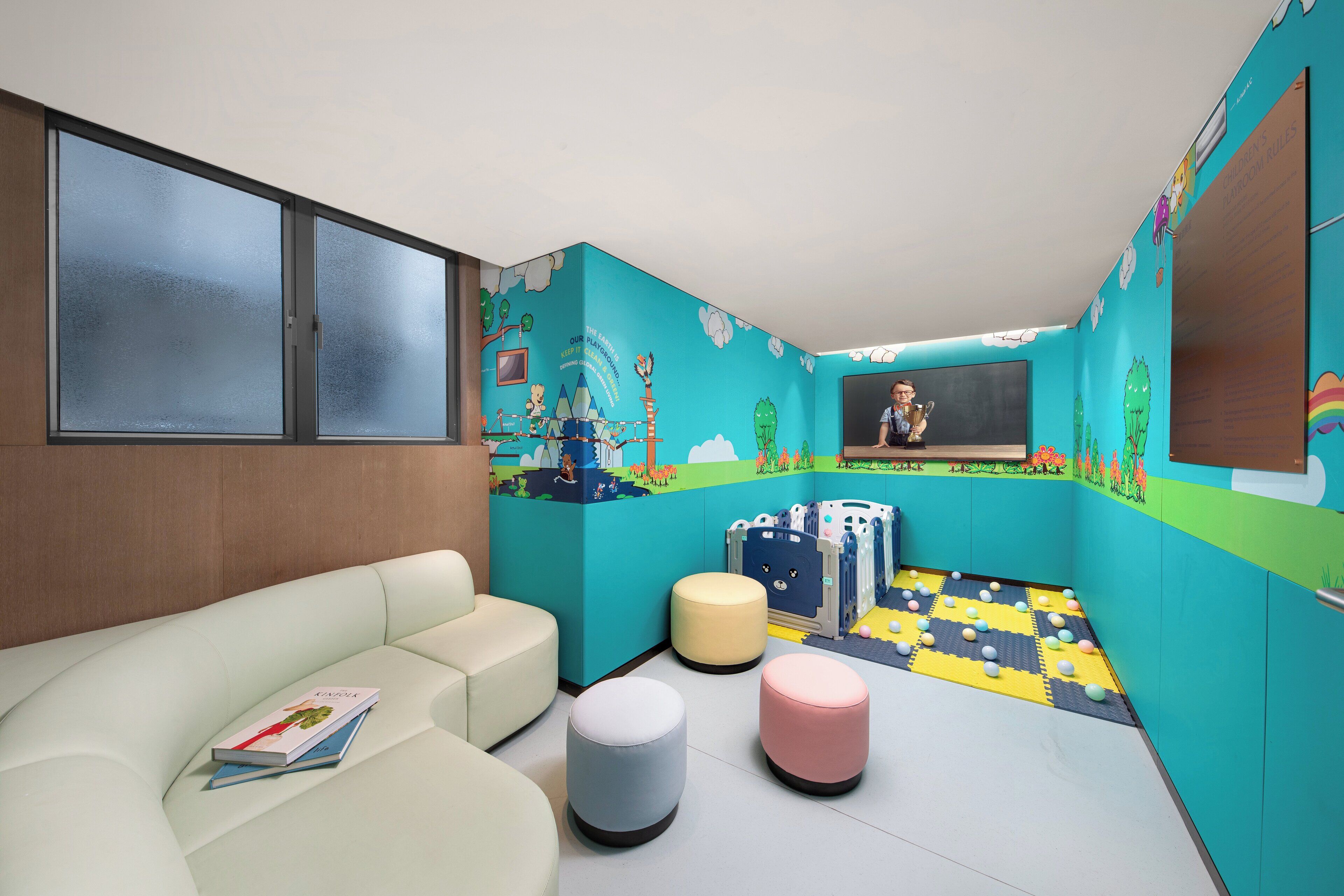 A children's playroom with a soft seating area, colorful play mats, and educational murals on the walls.