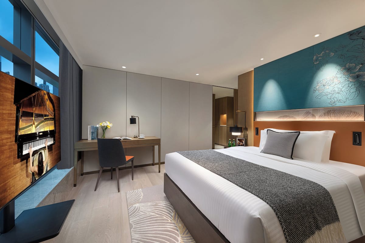 Una habitación de hotel moderna con una cama grande, un escritorio y un piano.